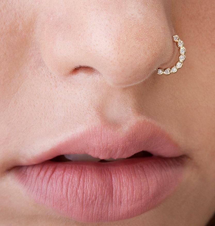 A close-up of a person's lips with a nose ring and a diamond-encrusted nose ring.