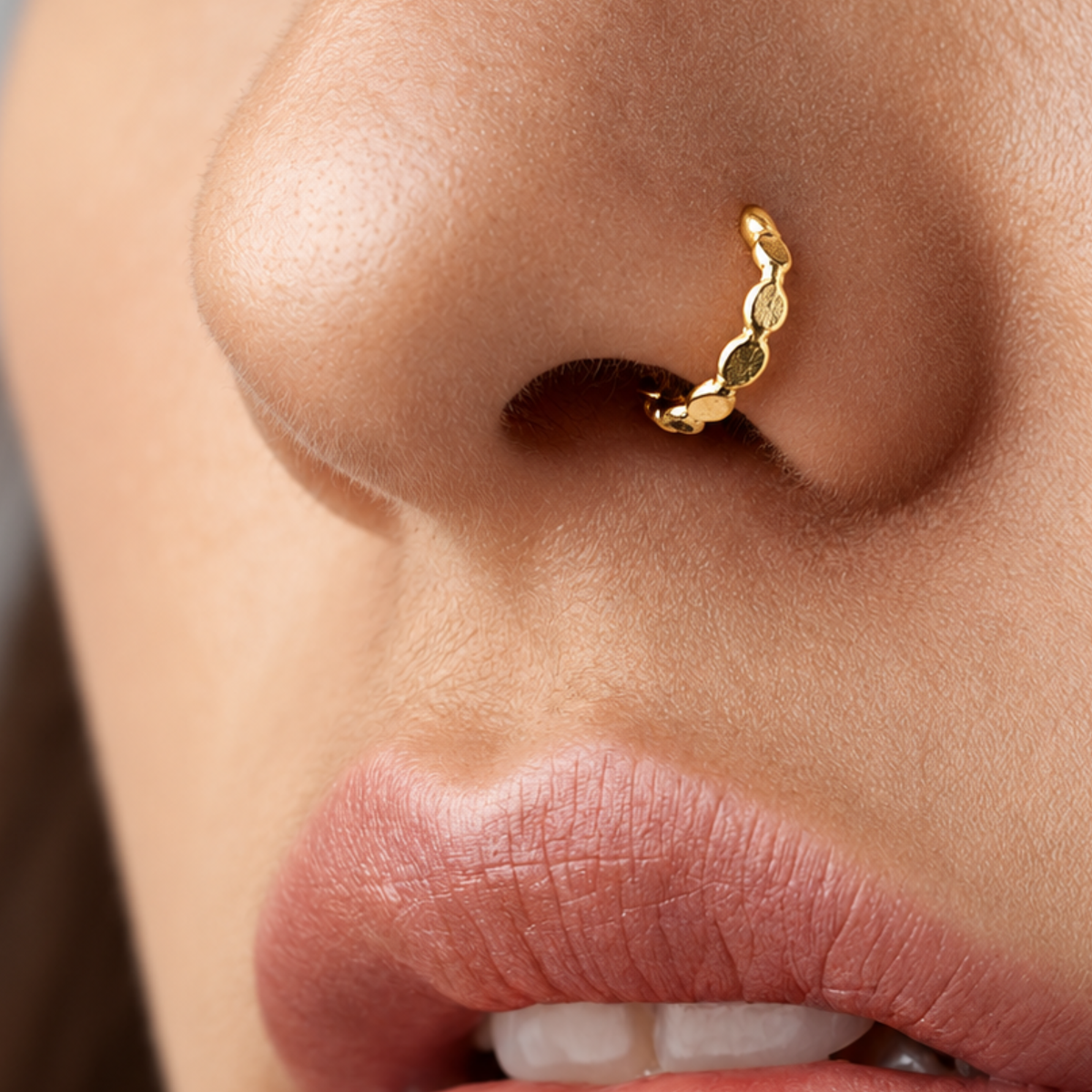 A close-up of a person's nose and lips, with a gold-colored nose ring visible.