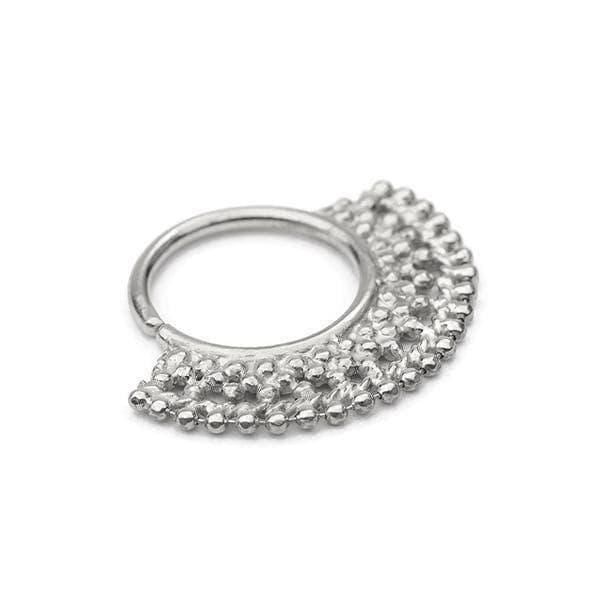 A silver-colored metal piercing ring with a decorative, textured design.