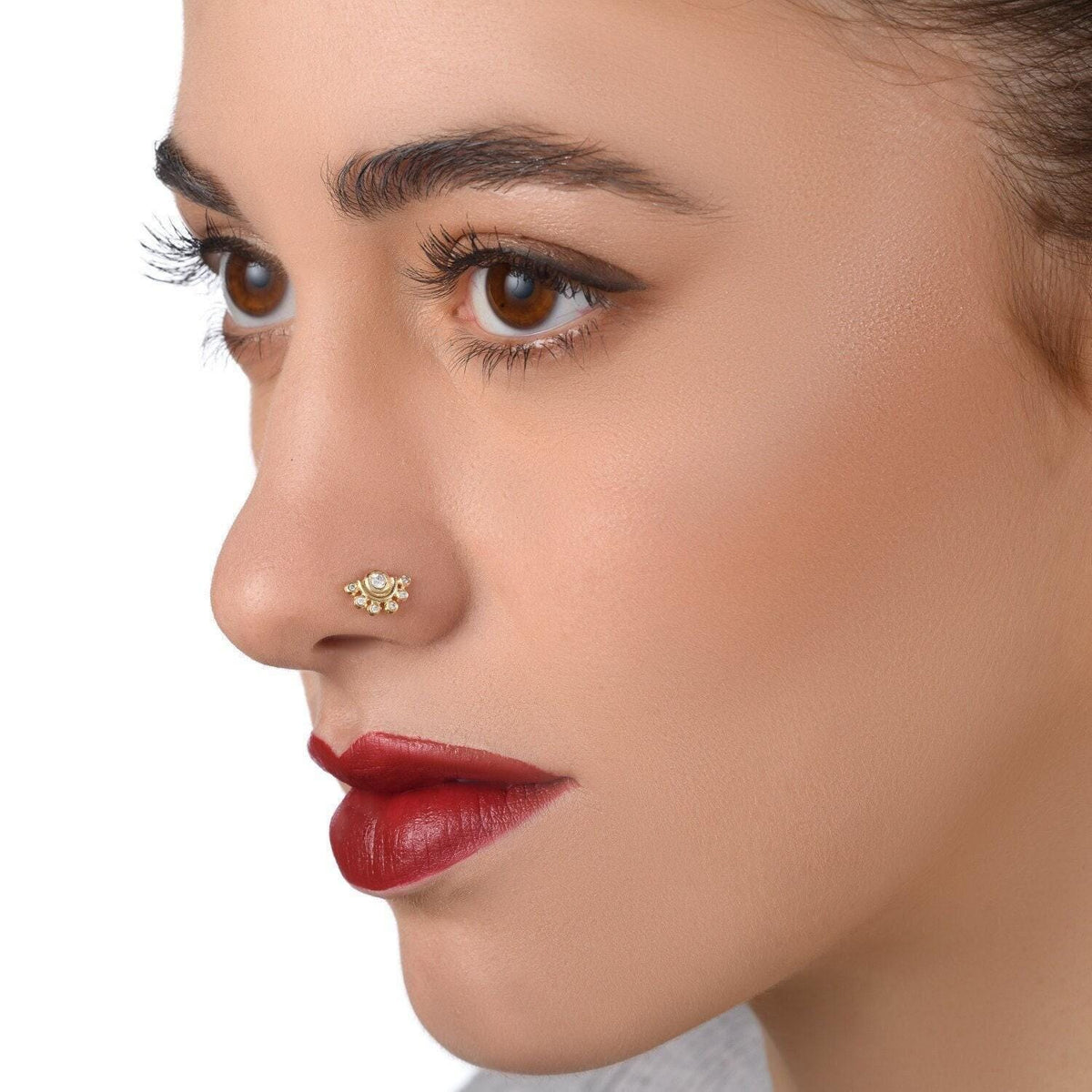 A close-up of a woman's face, focusing on her nose and lips. She has dark brown eyes and red lipstick.