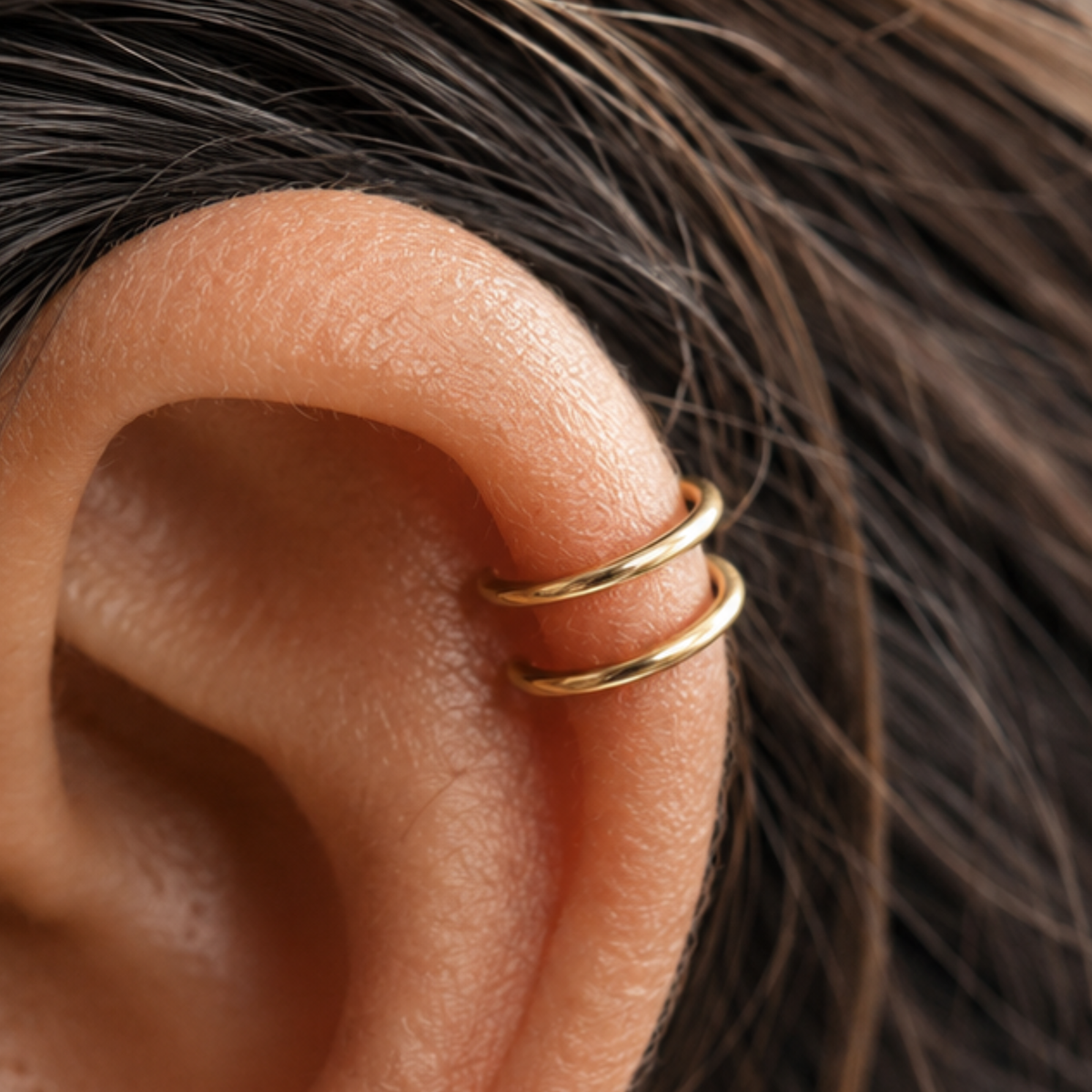 A close-up view of a person's ear with a gold-colored ring on the side.