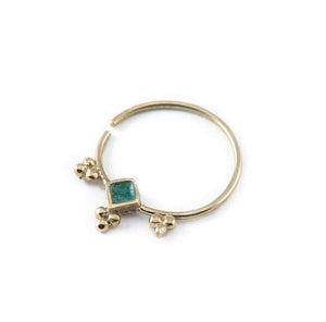 Dainty Gold Nose Ring: A gold-colored nose ring with a green gemstone in the center.