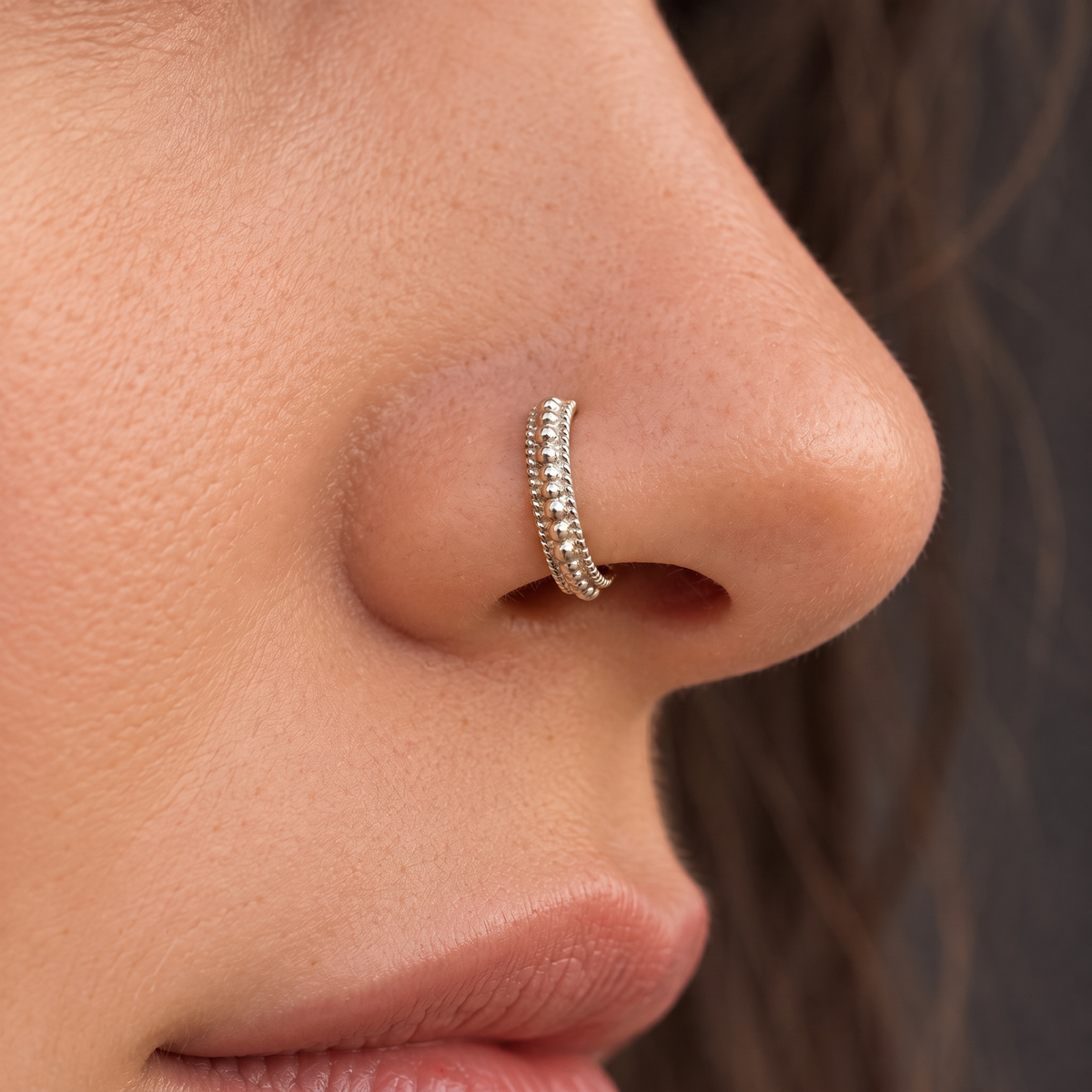 A close-up of a person's nose with a decorative nose ring.