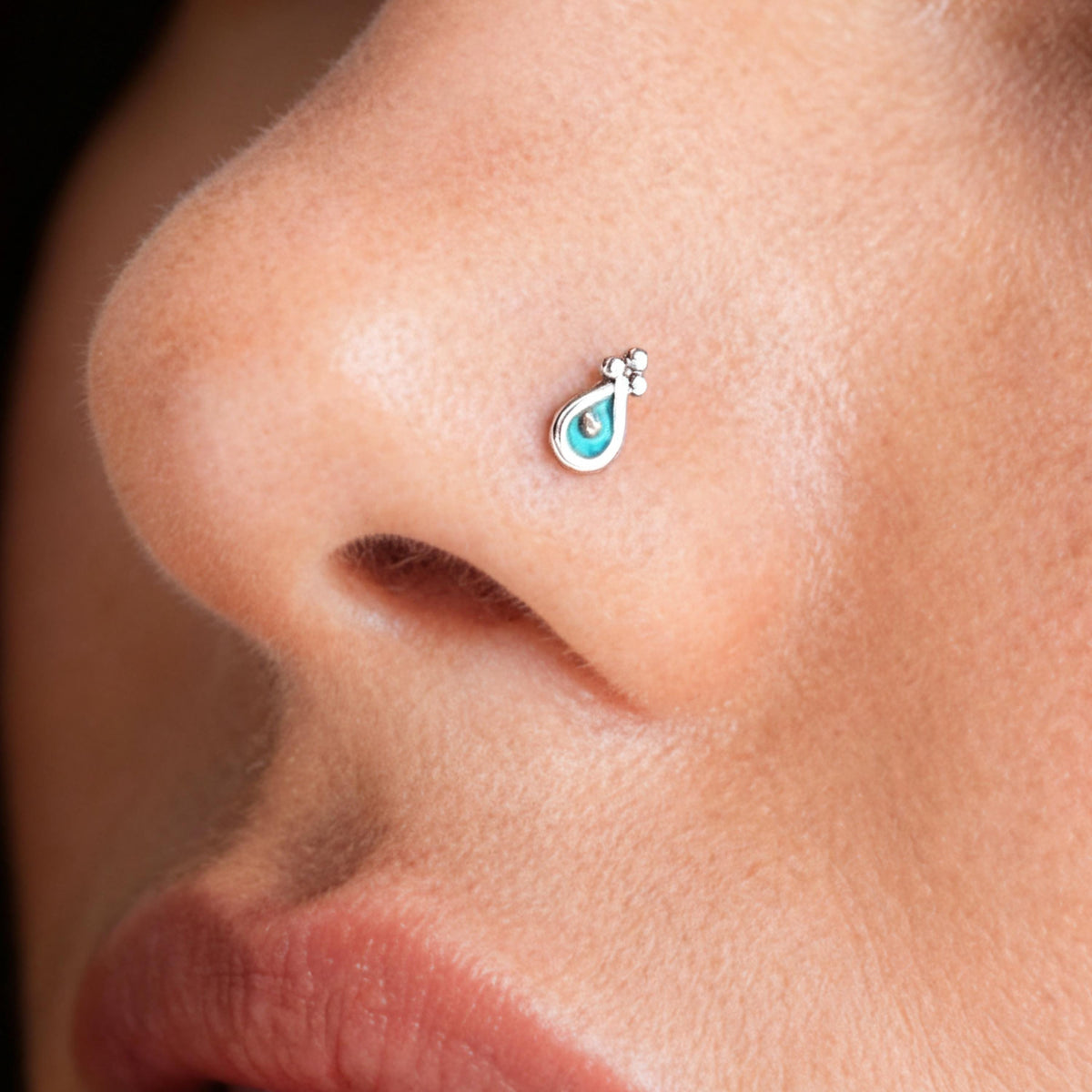 Boho Nose Stud: A close-up of a person's nose with a small, turquoise-colored nose stud or piercing.