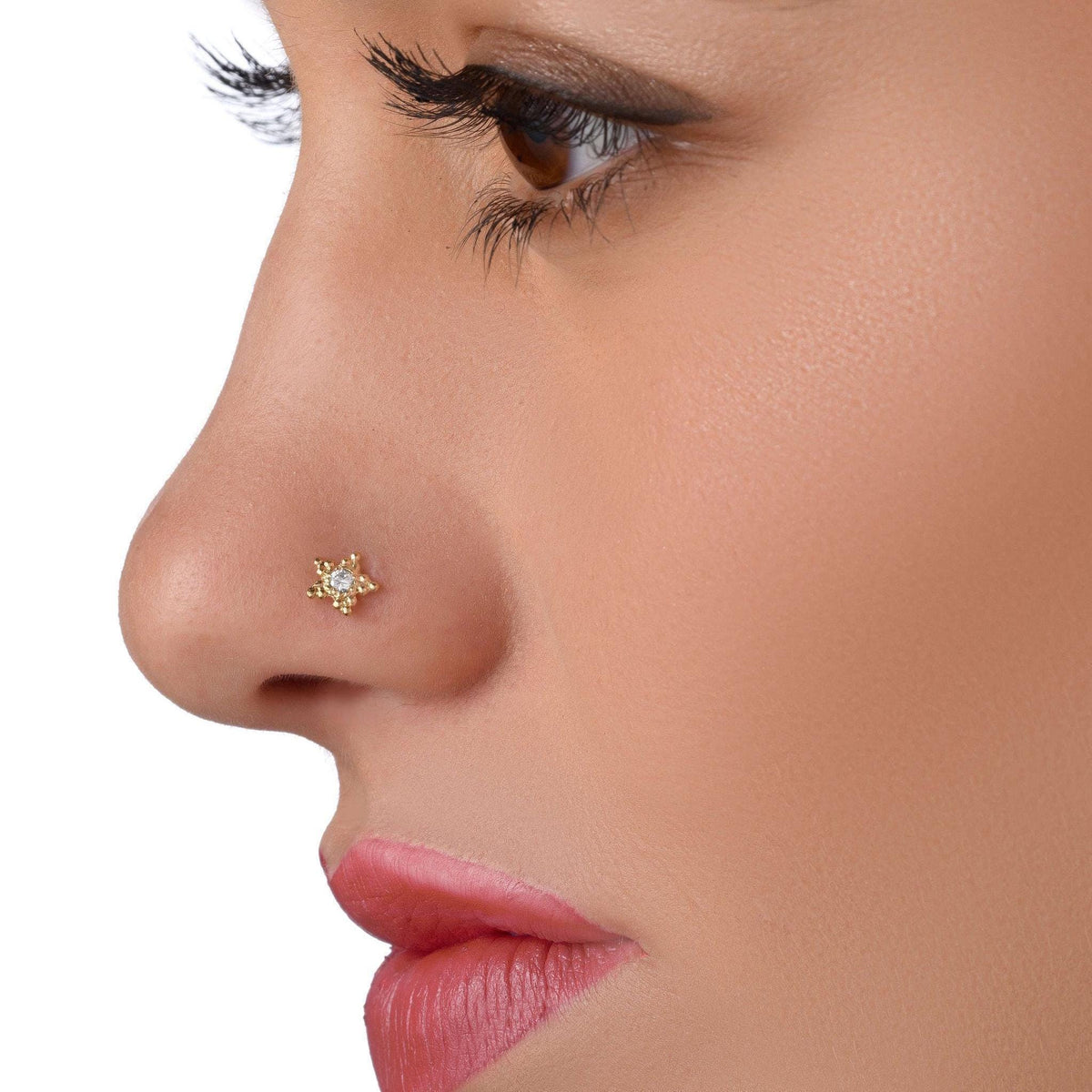 A close-up of a woman's face, focusing on her nose and lips. She is wearing a gold-colored nose stud with a star-shaped design.