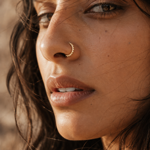 A close-up of a woman's face, focusing on her nose and lips, with a gold nose ring visible.