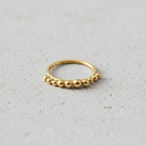 A gold ring with a row of small, round balls or stones set in the center.