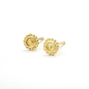 A pair of gold earrings with a flower-like design on the center.
