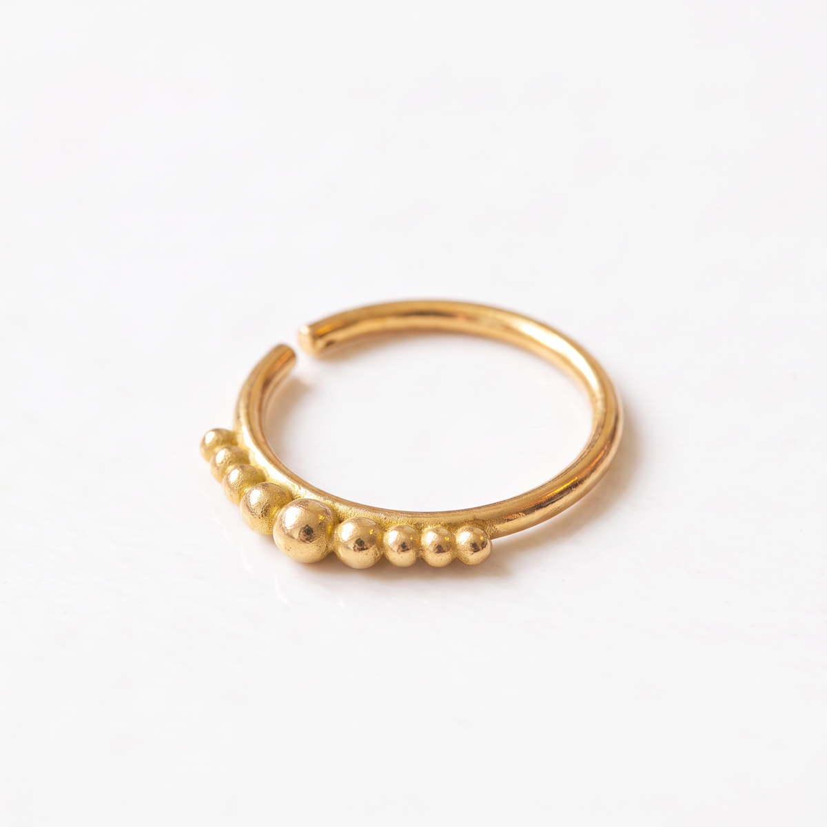 A gold-colored ring with a row of small, round, shiny balls or stones along the edge.