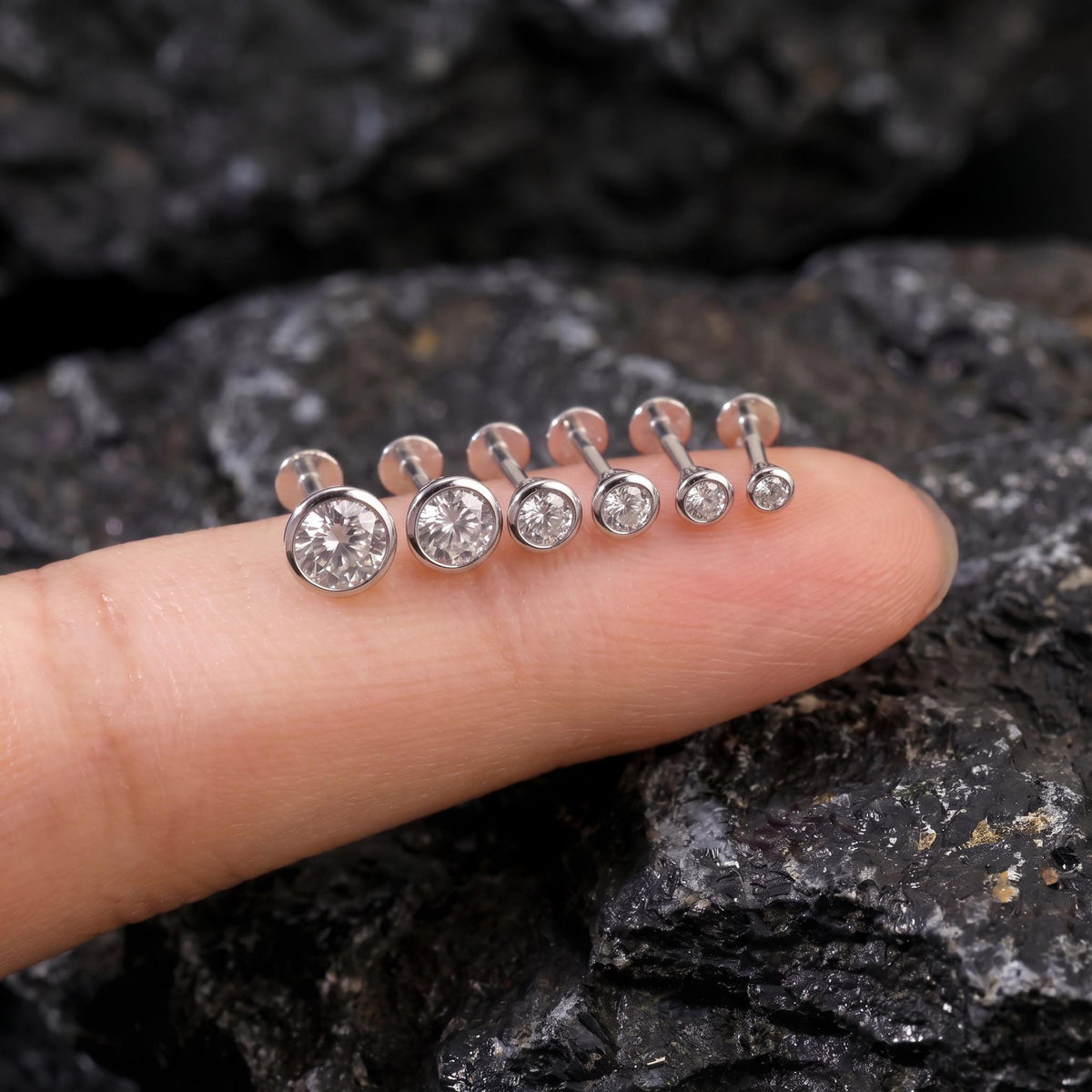 A close-up image of a person's finger wearing a row of diamond-encrusted earrings.