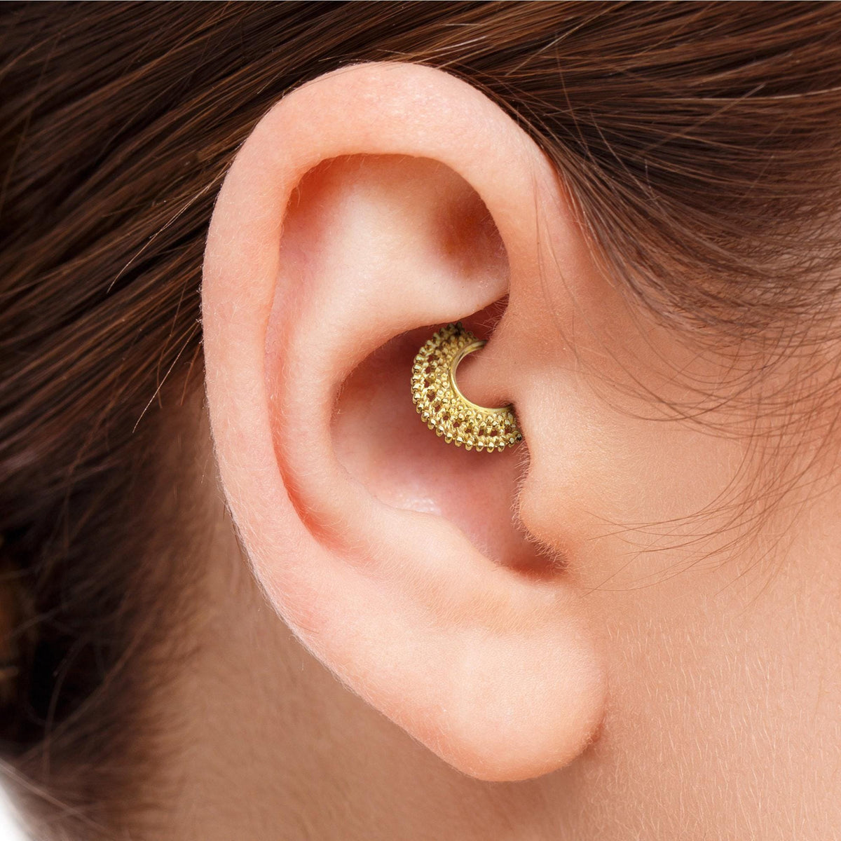Tribal Daith Hoop Earring: A close-up view of a person's ear with a gold-colored earring inserted.