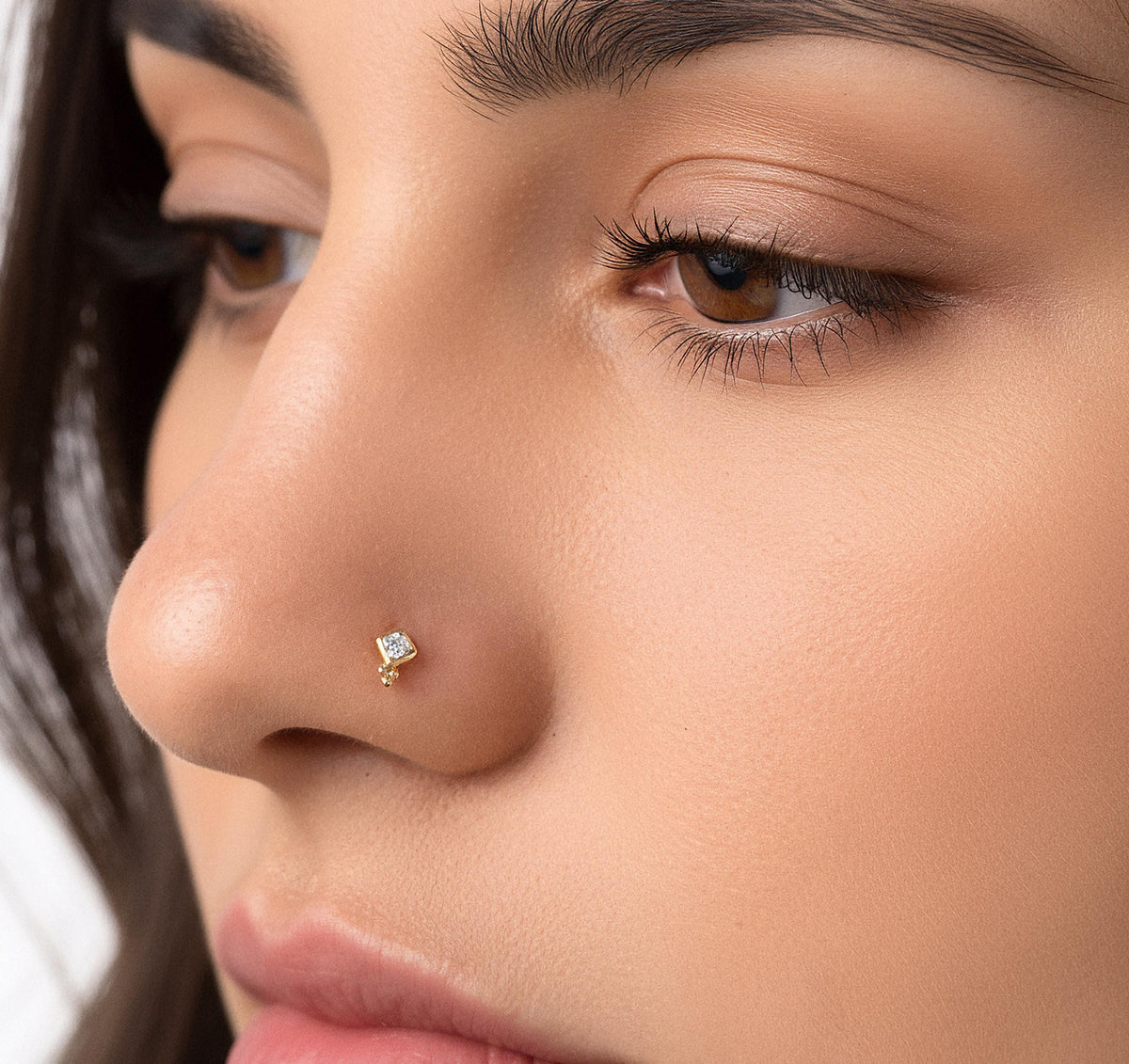 A close-up of a woman's face, focusing on her nose and the small nose stud.