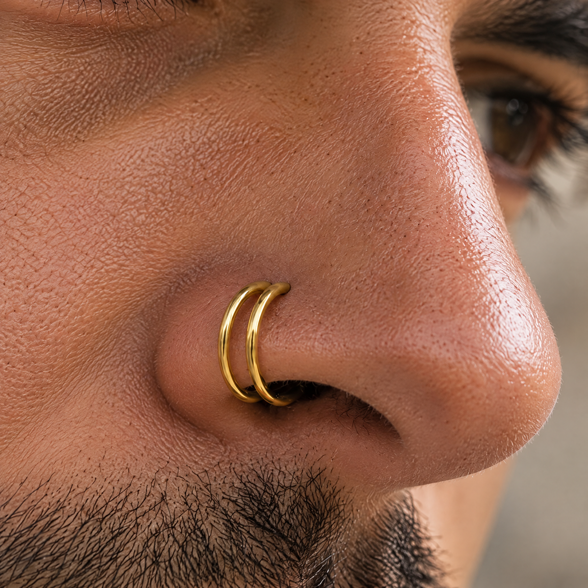 A close-up of a person's nose and nostrils, with a gold nose ring visible.