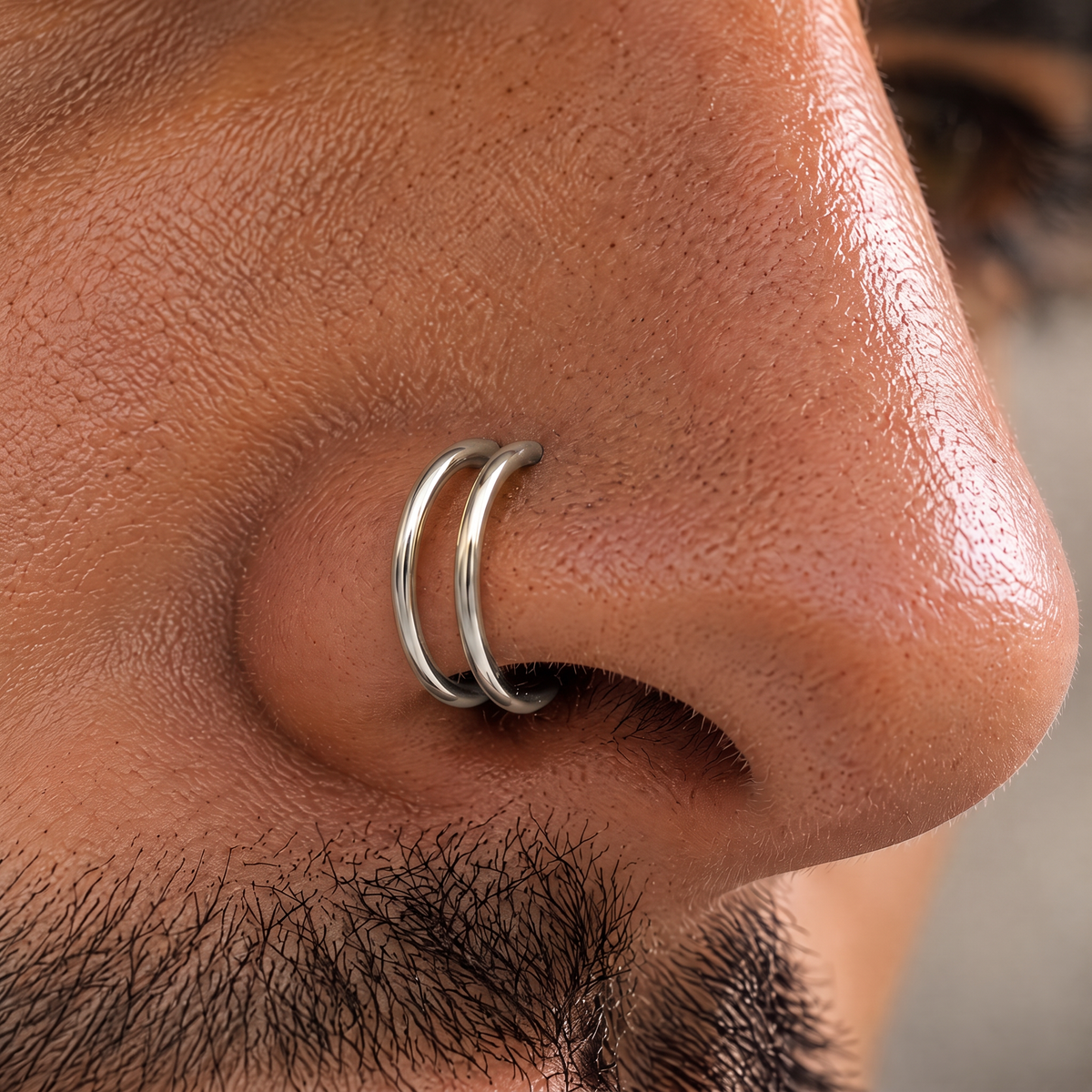 A close-up of a person's nose with a silver nose ring.
