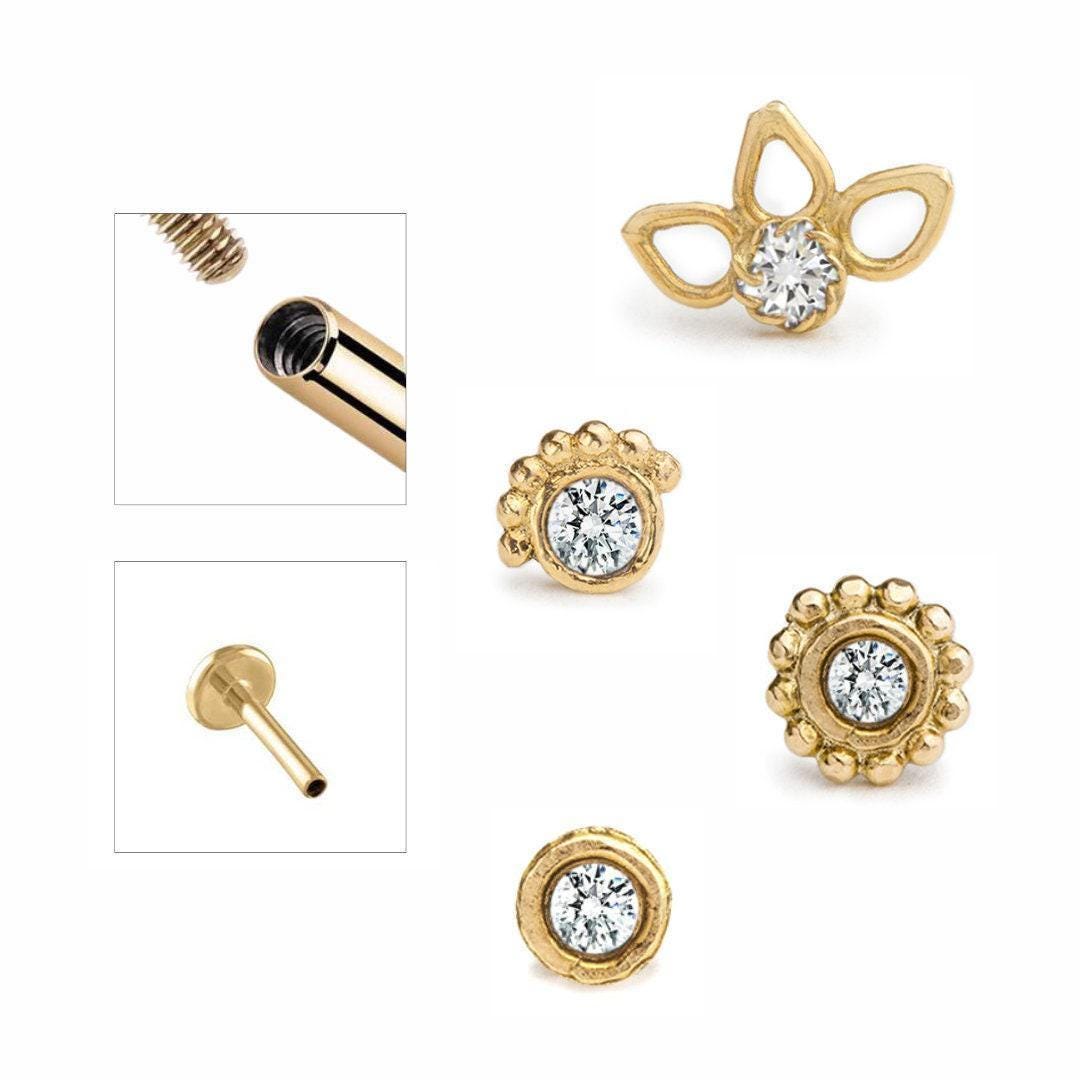 Various gold-colored jewelry pieces, including earrings and a nose stud, with a central focus on the earrings and nose stud.