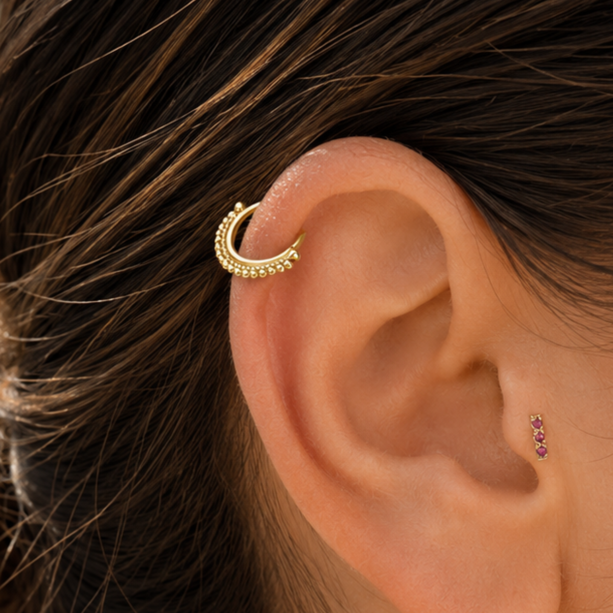 A gold earring with a small gemstone is visible in the image.