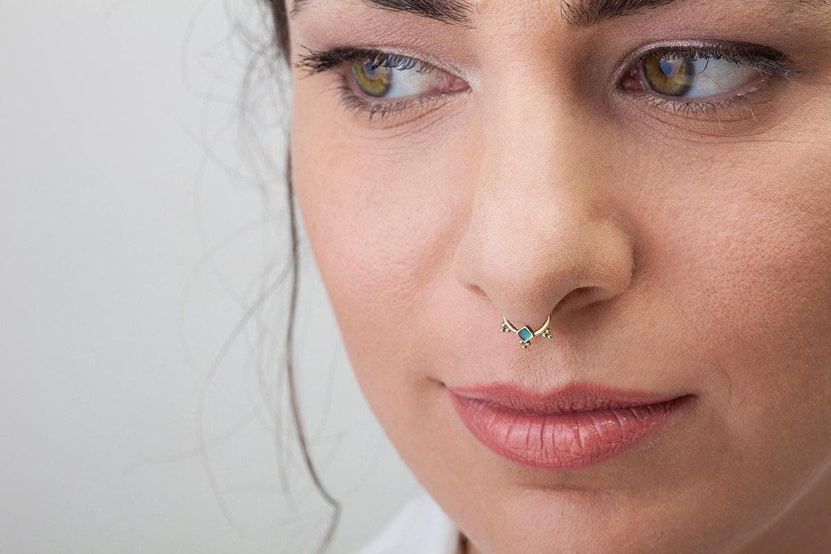 A close-up of a woman's face, focusing on her nose and lips, with a piercing in her nose.