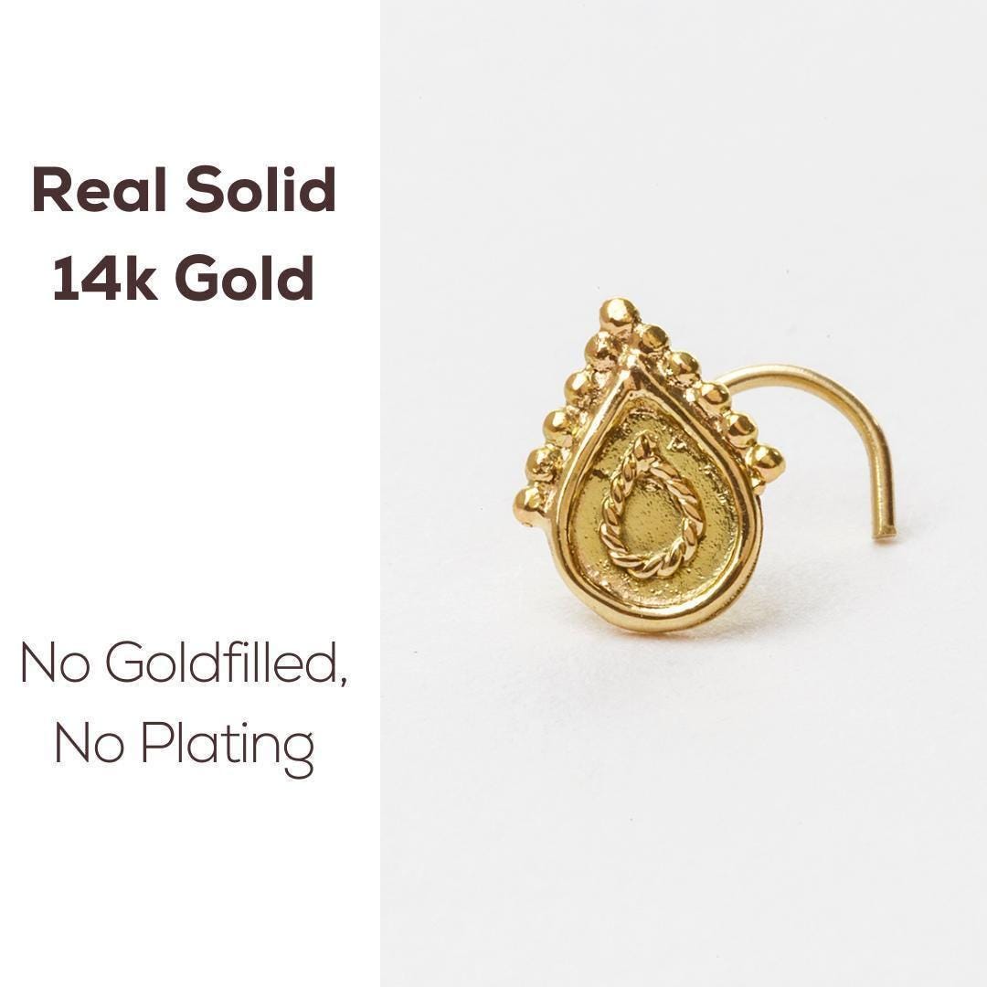 a gold nose ring with a decorative design on the front.