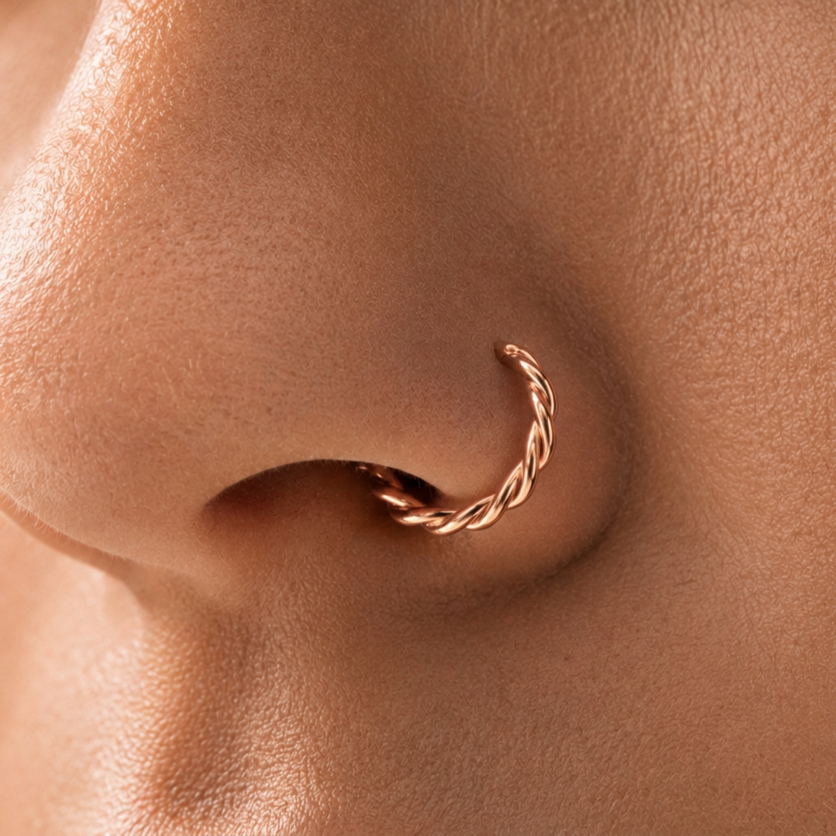 A close-up of a person's nose with a twisted metal nose ring.