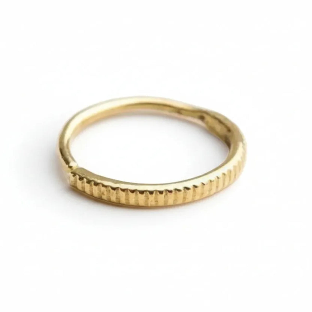 A gold ring with a thin, textured band is shown against a plain white background.