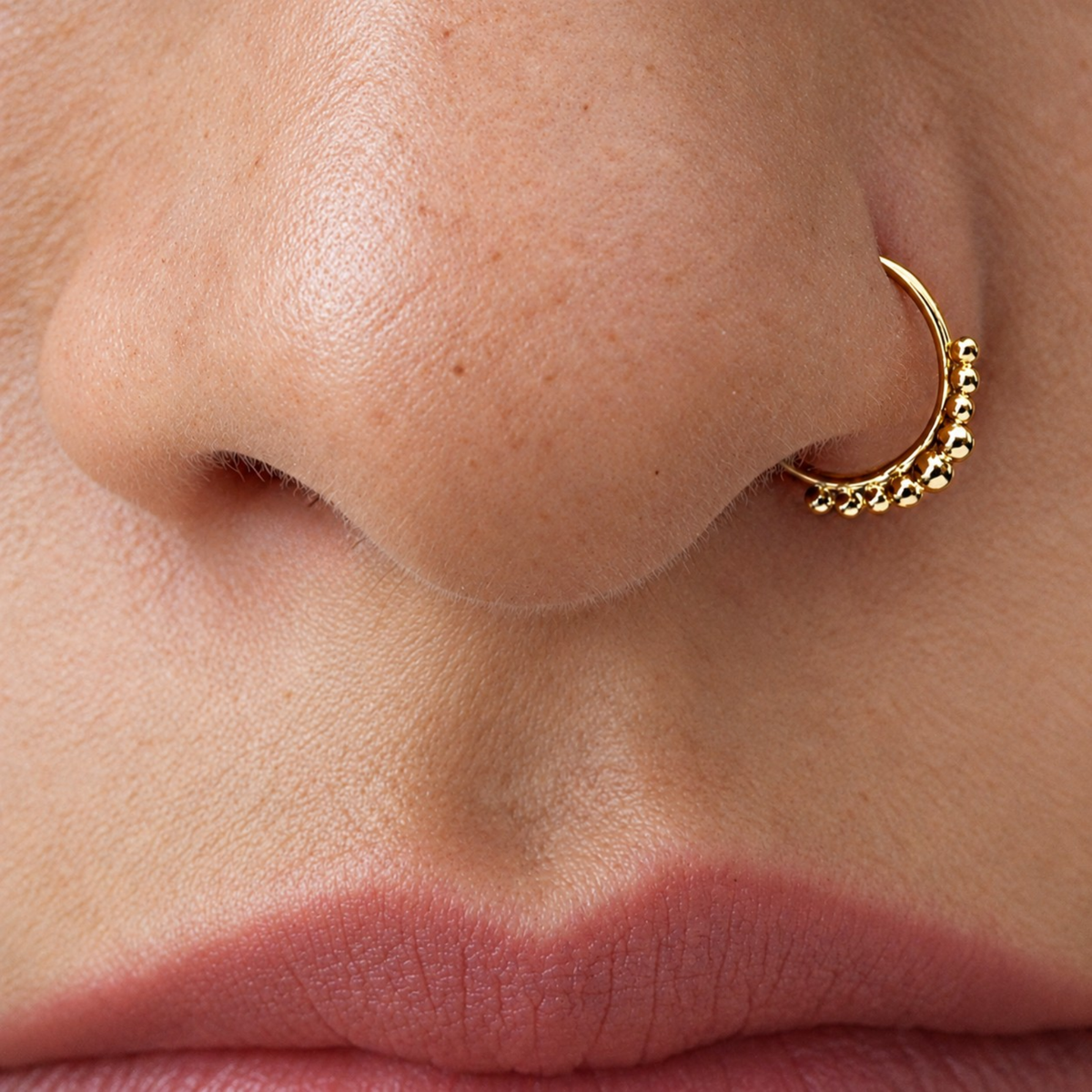 A close-up of a person's nose and lips, with a gold hoop earring visible.