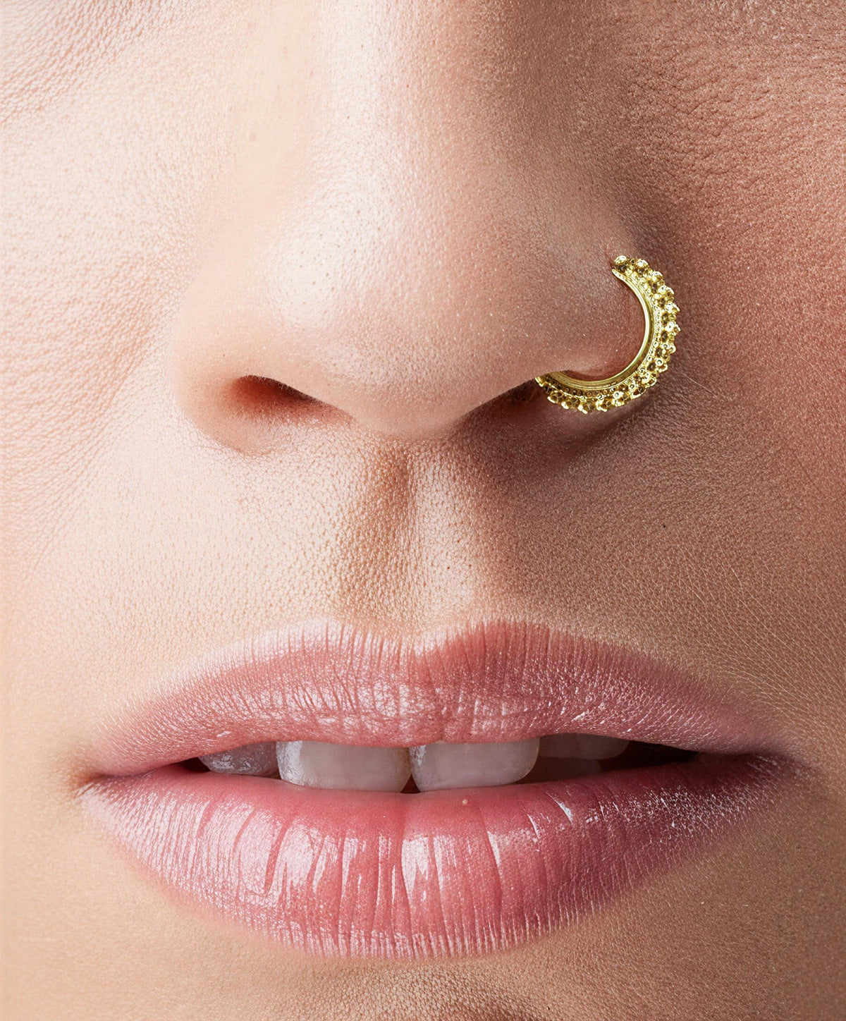 Gold Nose Ring: A close-up of a person's face, focusing on their lips and nose.