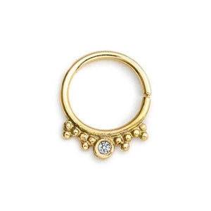A gold-colored ring with a diamond-like center stone and a decorative element around the edge.