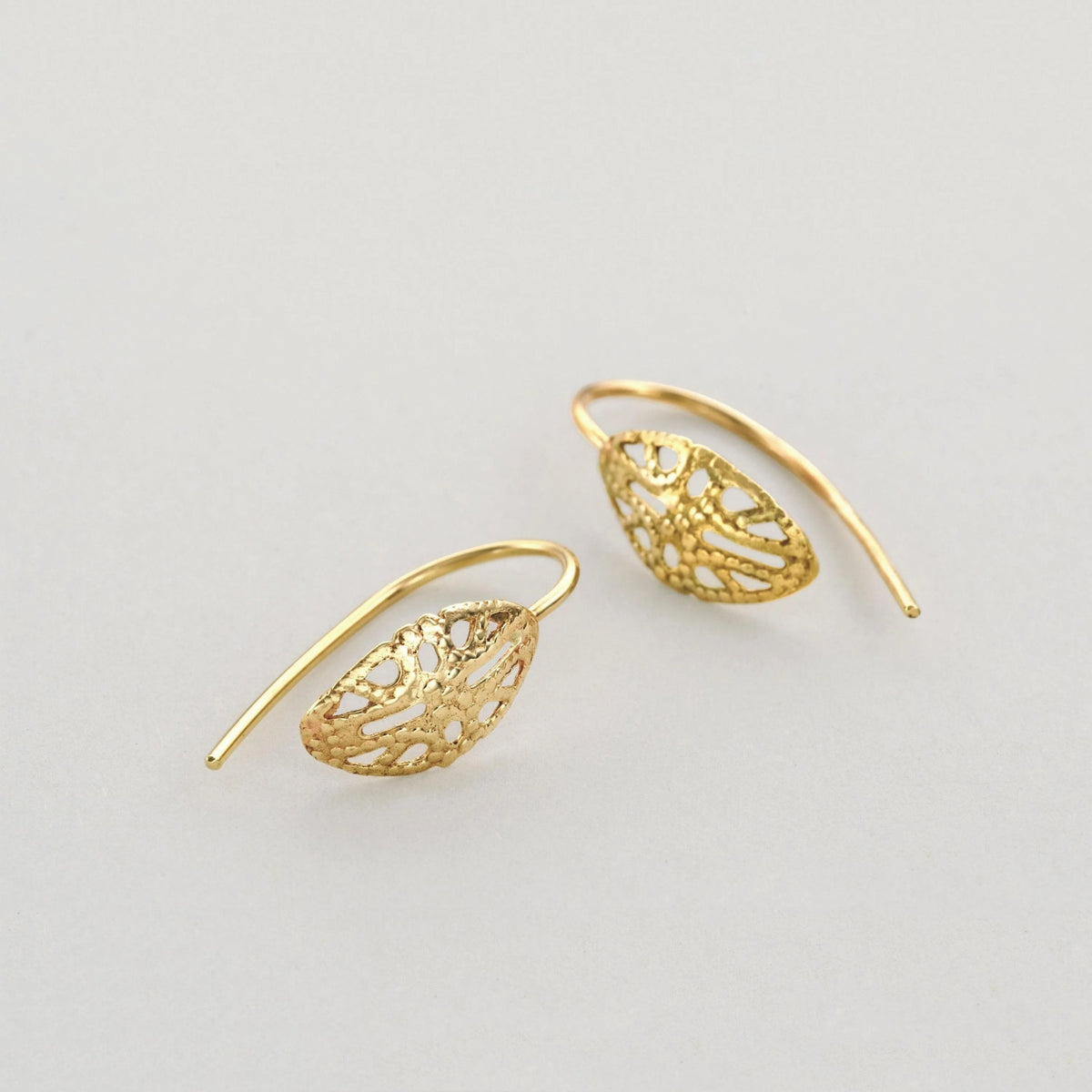 A pair of gold earrings with intricate leaf-like designs.