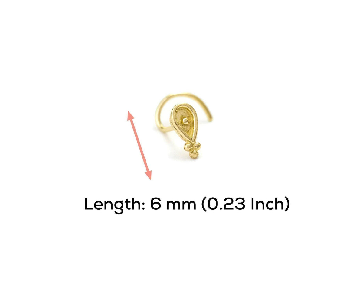 A gold-colored nose ring with a small decorative element is shown against a white background.