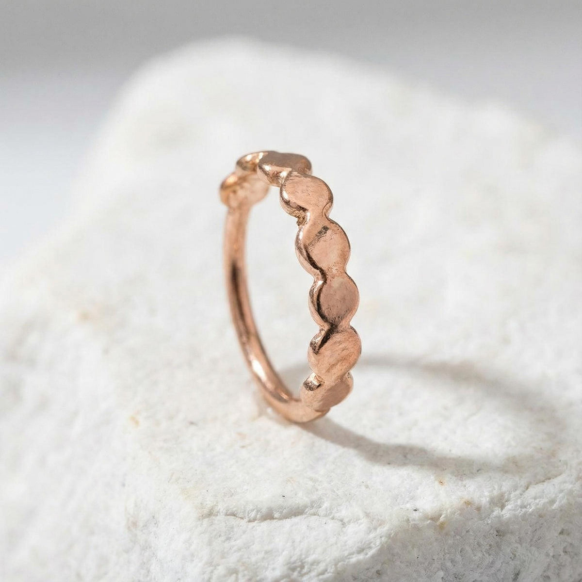Rose Gold Nose Ring: A single, intricately designed ring with a unique, textured pattern sits on a white surface.