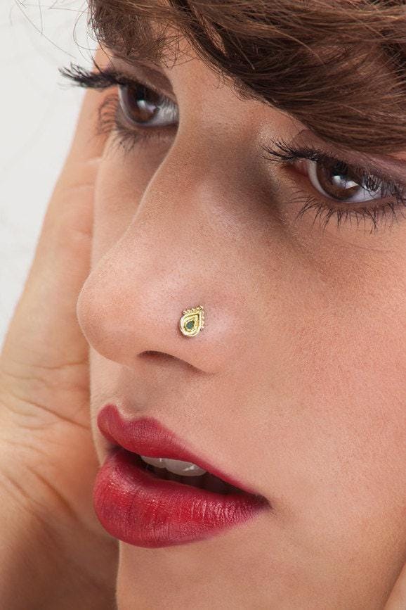 A close-up of a woman's face, focusing on her nose and lips, with a gold nose stud visible.