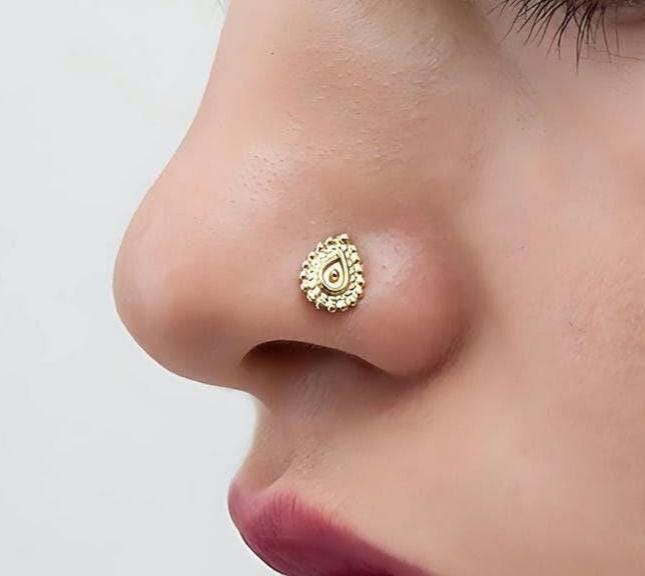 Gold Nose Stud: Statement Size: A close-up of a woman's face, focusing on her nose and lips, with her eyes closed.