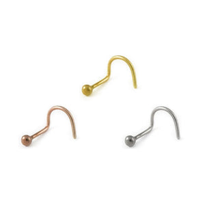 four different colored metal nose studs, each with a round ball at the end, arranged in a row against a white background.