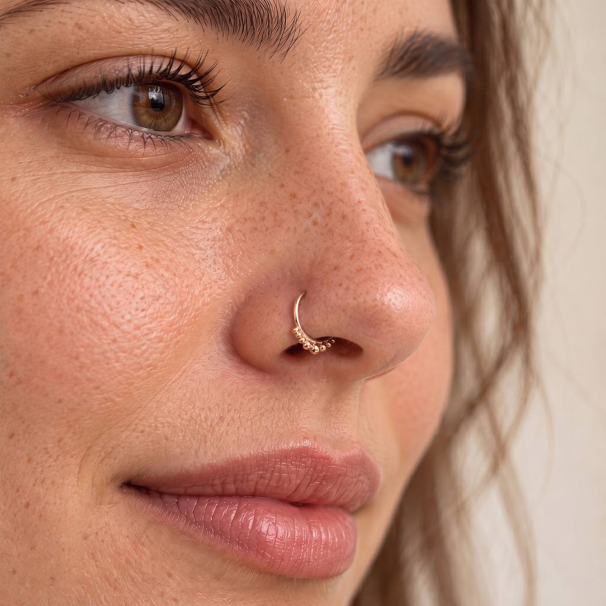 A close-up of a woman's face, focusing on her nose and lips. She has a nose ring and her eyes are brown.