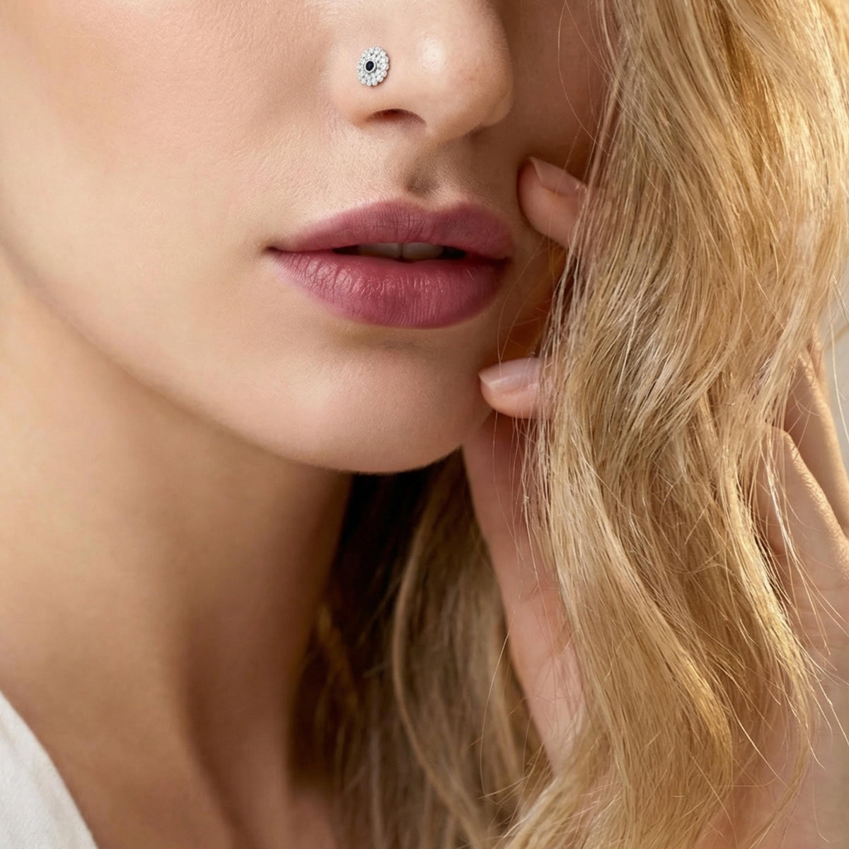 A close-up of a woman's face, focusing on her nose and lips, with her hand gently touching her hair.