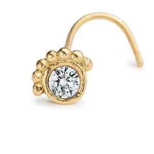 A gold-colored nose stud with a clear gemstone set in the center.