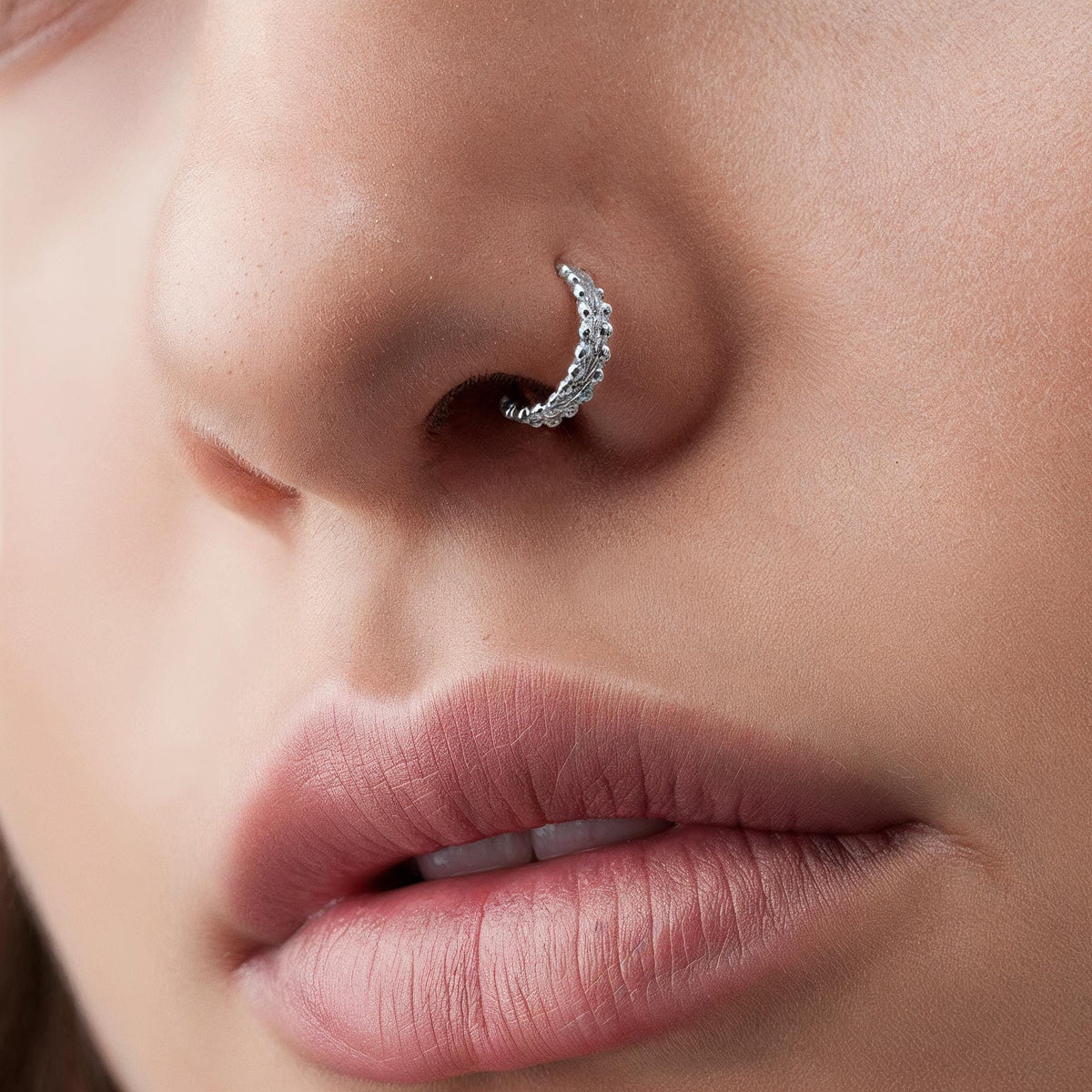 A close-up of a person's nose and lips, with a silver nose ring visible.