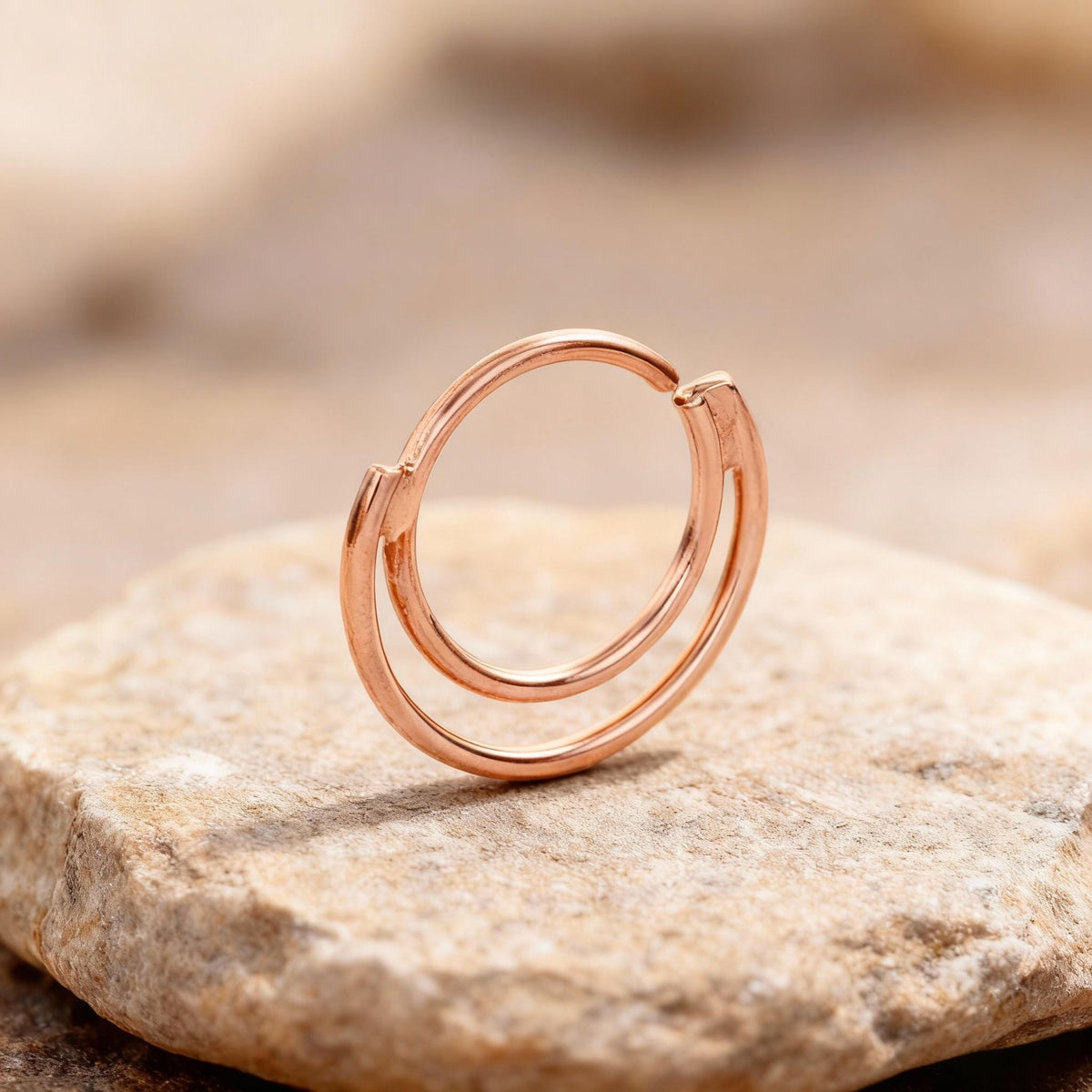 A copper-colored ring with a circular design sits on a rock.