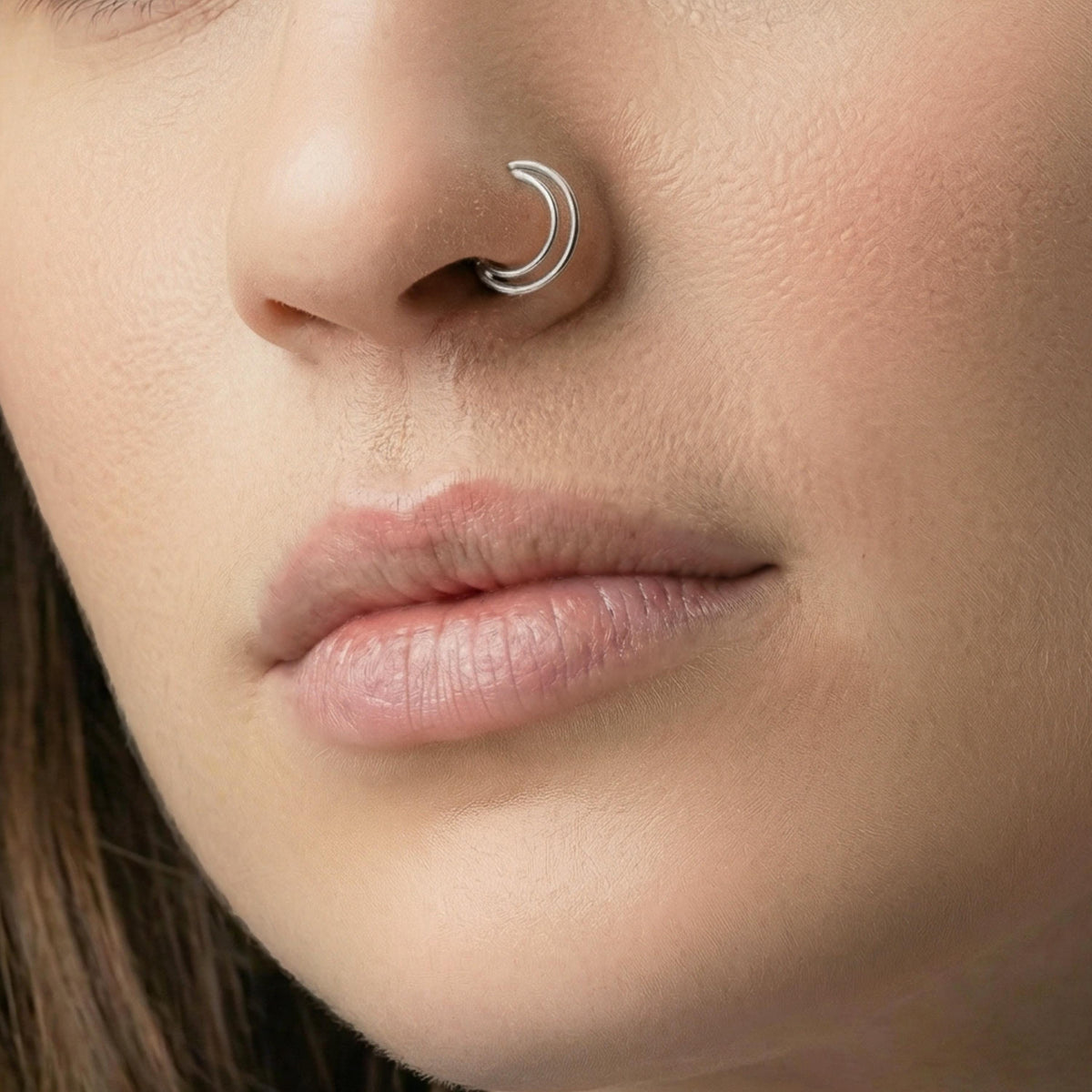 A close-up of a person's face, focusing on their nose and lips wearing white gold hoop.