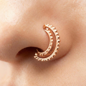 A close-up of a person's nose with a decorative gold-colored nose ring.