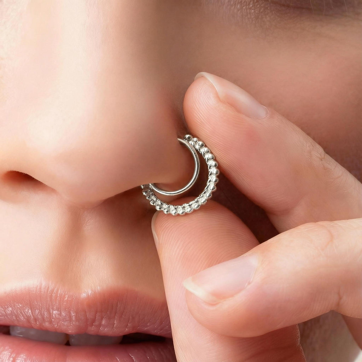 A close-up of a person's face, focusing on their nose and fingers, with a silver hoop earring visible.