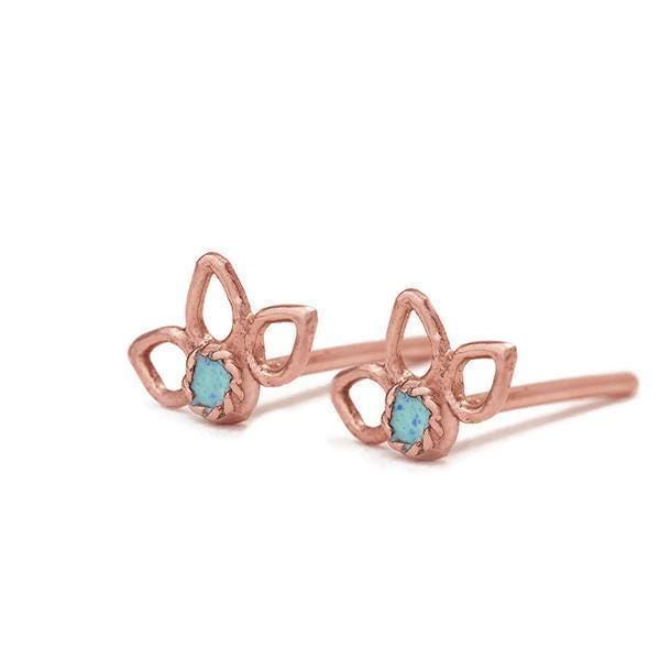 a pair of rose gold earrings with blue gemstones, resting on a white background.