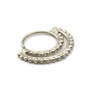 A silver-colored metal piercing ring with a row of small, round beads or stones along the edge.
