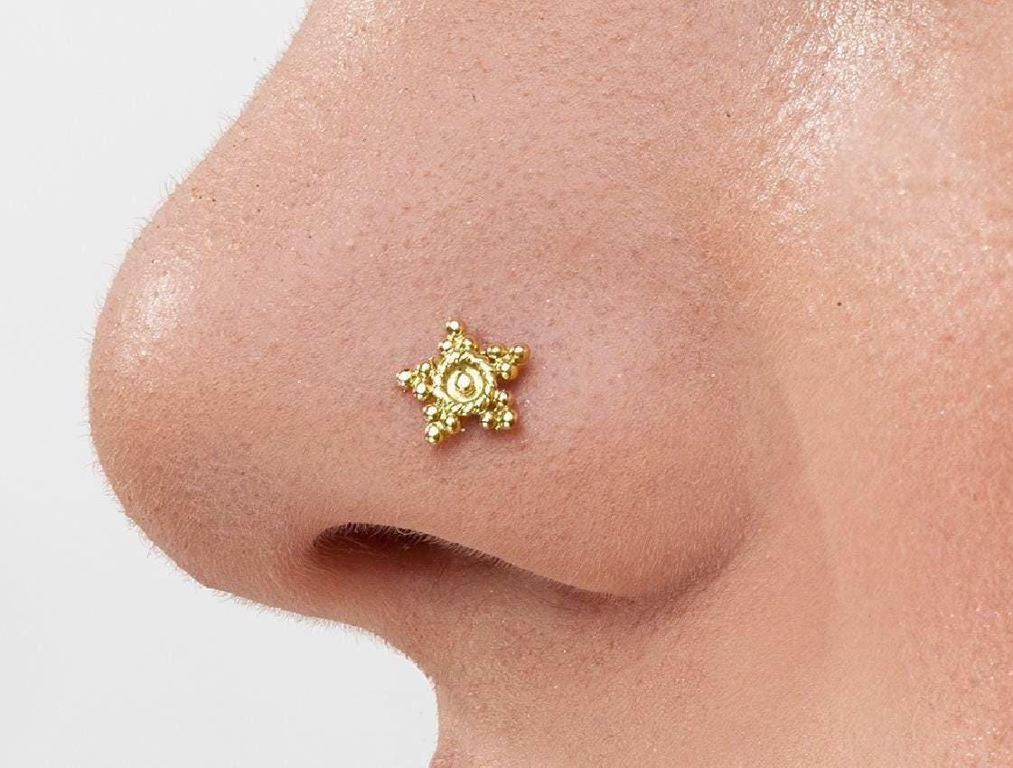 Indian Star Nose Stud: A close-up of a person's nose with a small, ornate gold star-shaped nose stud.