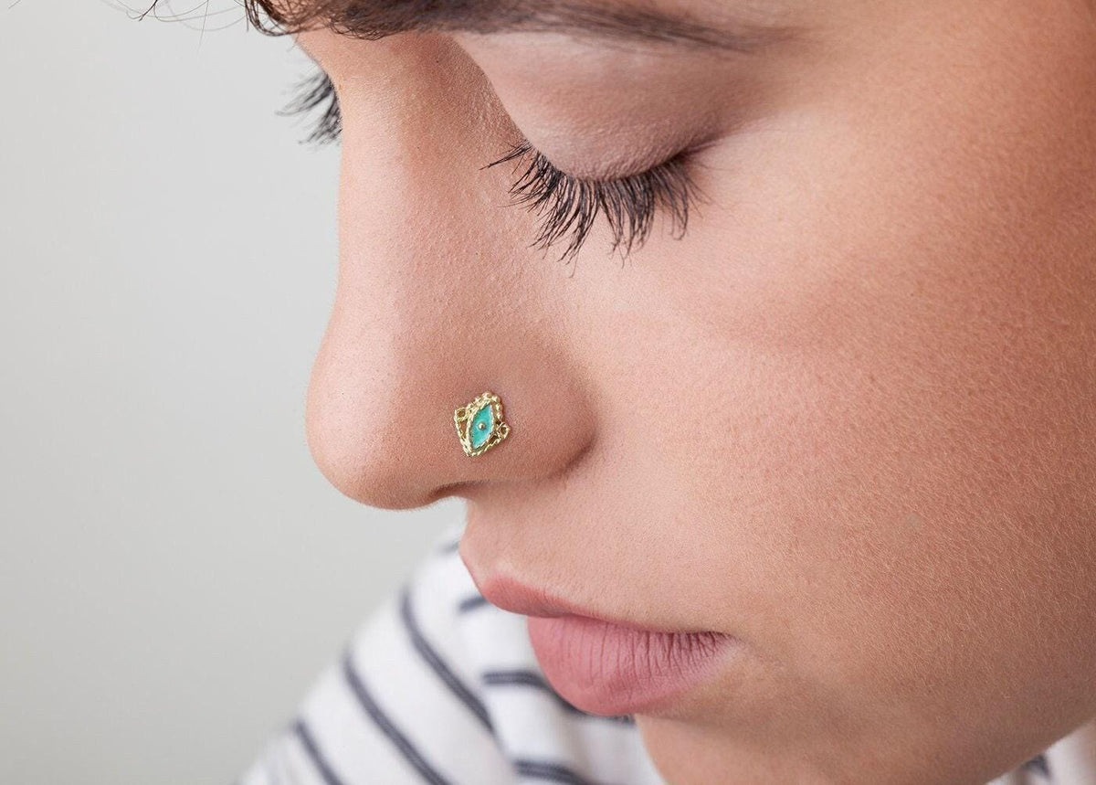 Gold Nose Stud: A close-up of a person's face, focusing on their nose and the small, ornate nose ring.