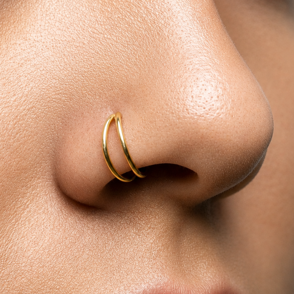 A close-up of a person's nose with a gold-colored nose ring.