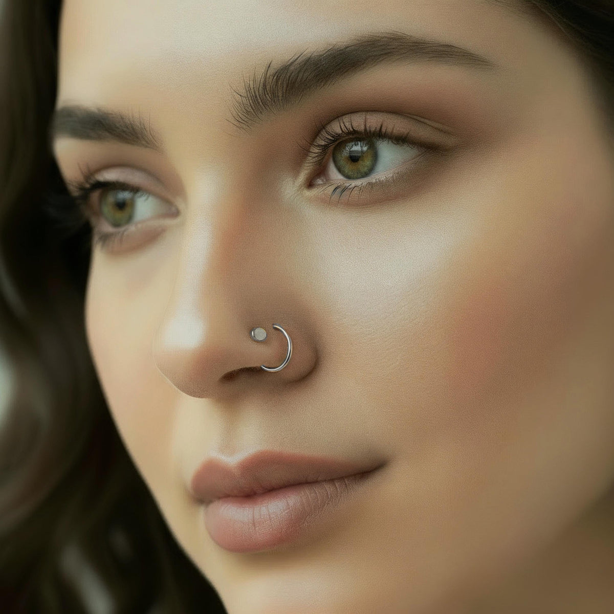 A close-up portrait of a woman with a nose ring, her eyes gazing off to the side.