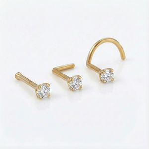 Three gold-colored diamond-encrusted nose piercings are shown against a white background.
