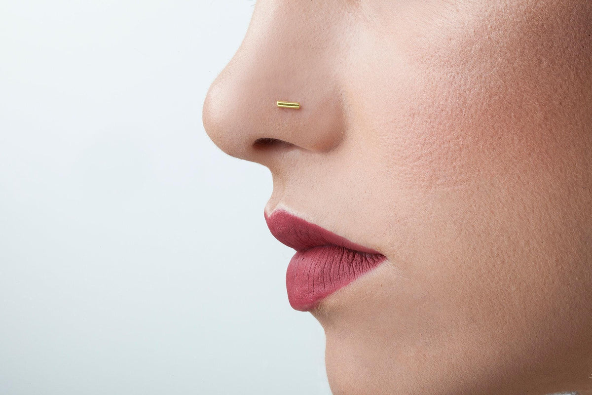 Gold Nose Stud Bar: A close-up of a person's face, focusing on their nose and lips.