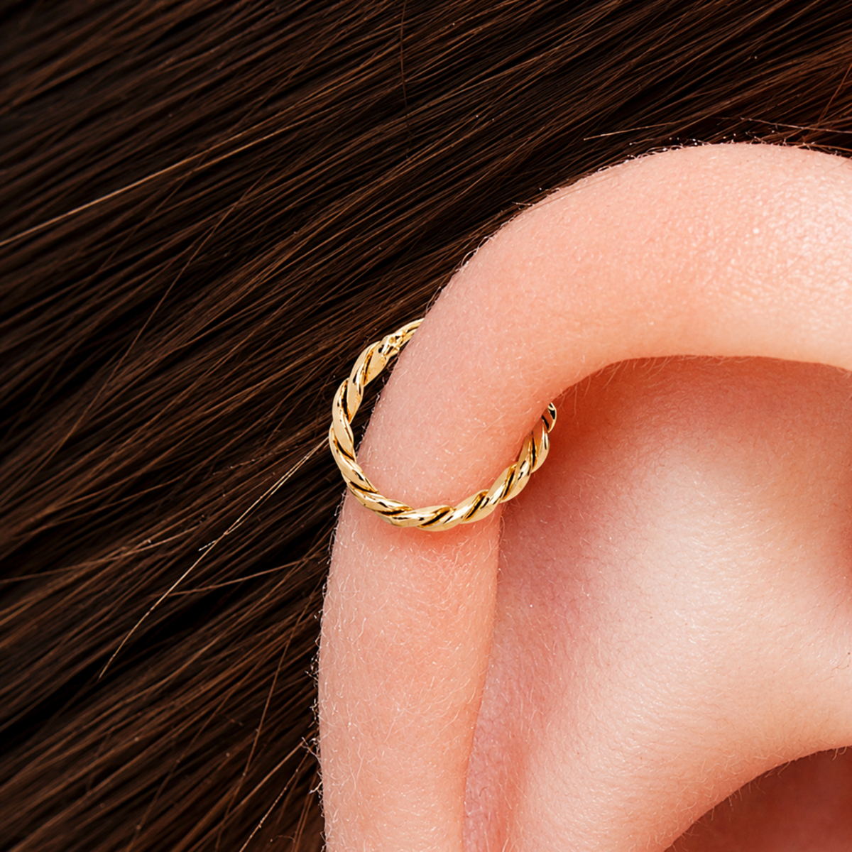 A gold-colored metal ring is placed on the side of an ear.